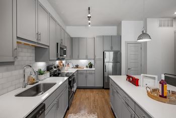 A modern kitchen with a white countertop and grey cabinets.